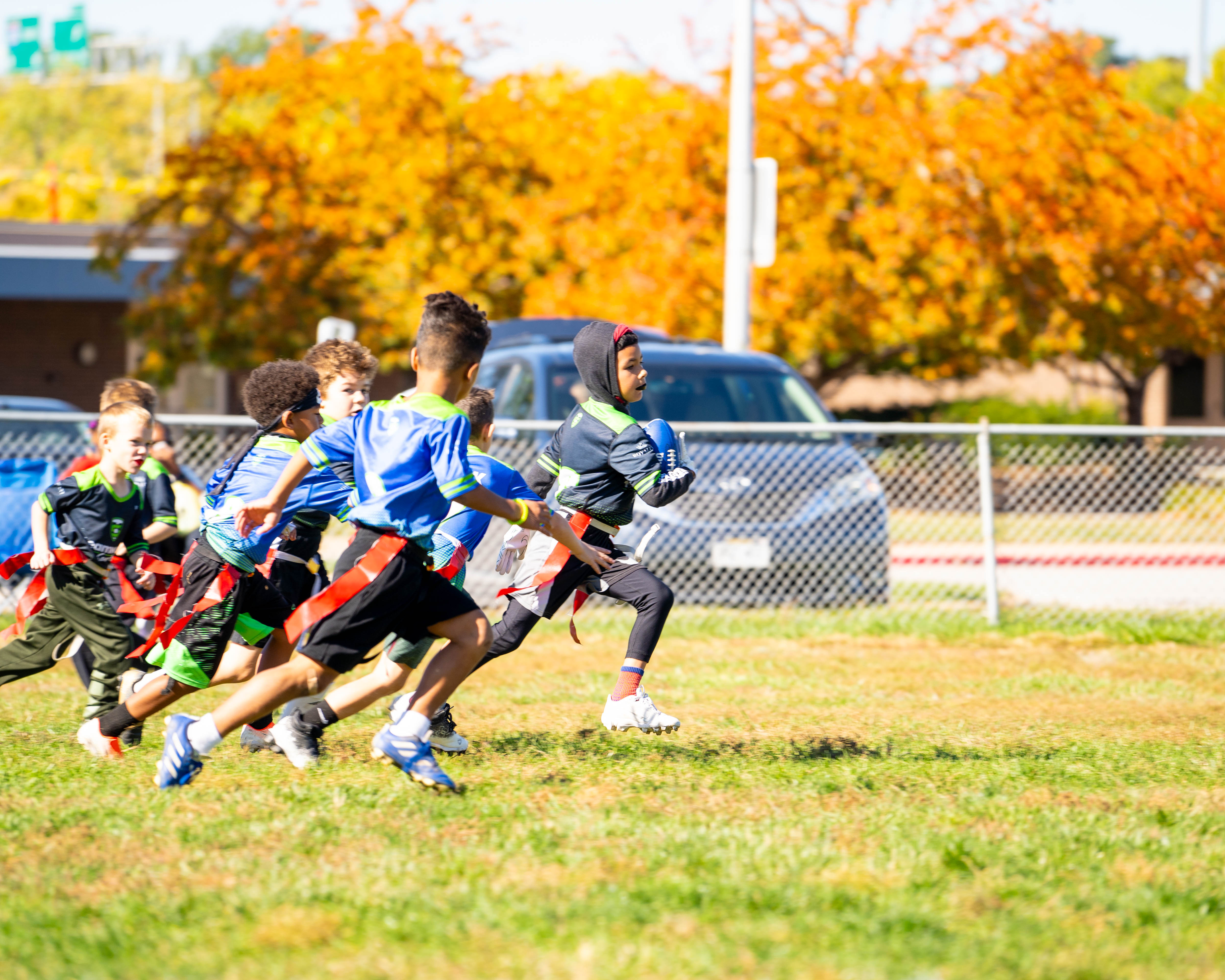 Young players chasing down a ball carrier during a fall flag football game